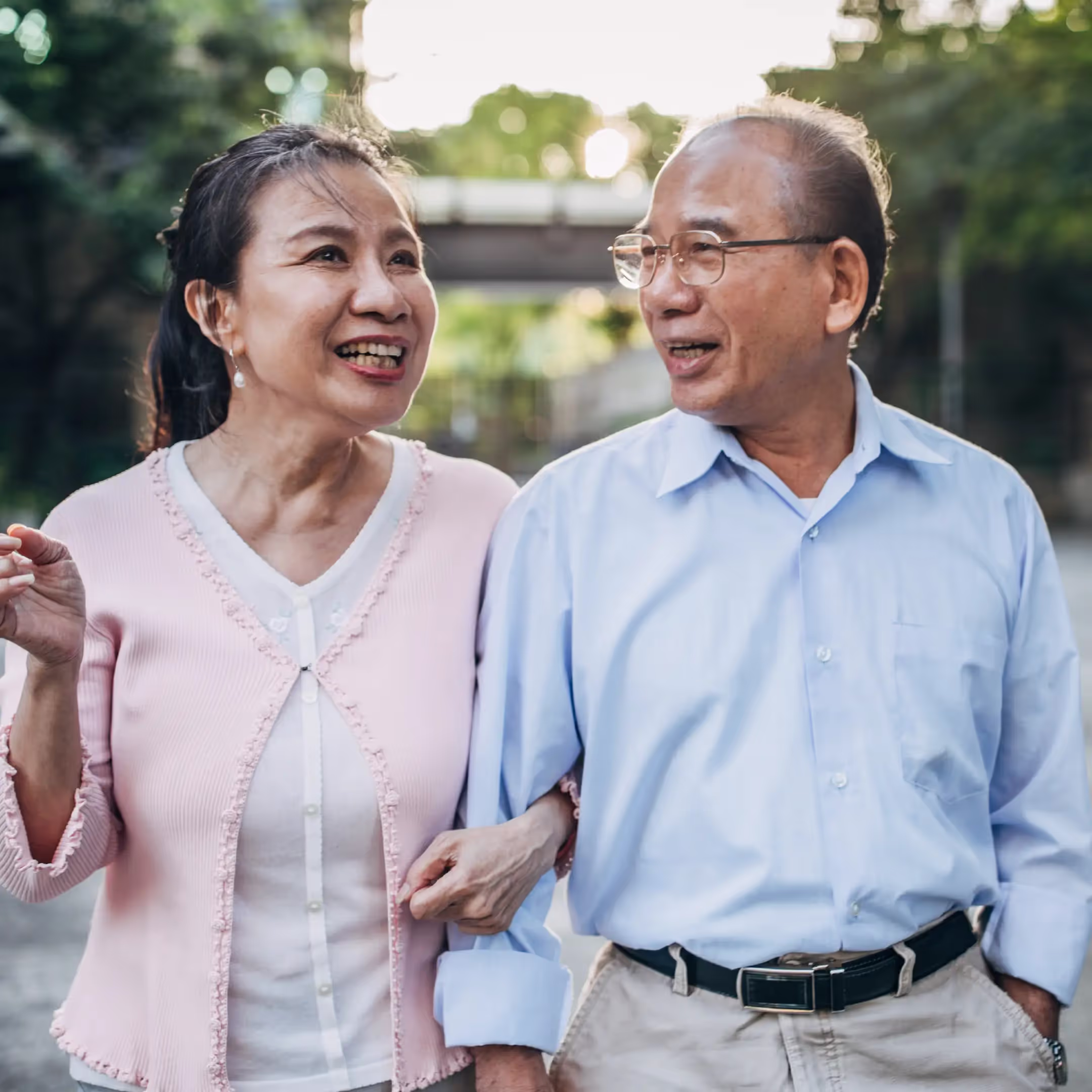 An elderly asian couple walking on a path hand in hand while smiling