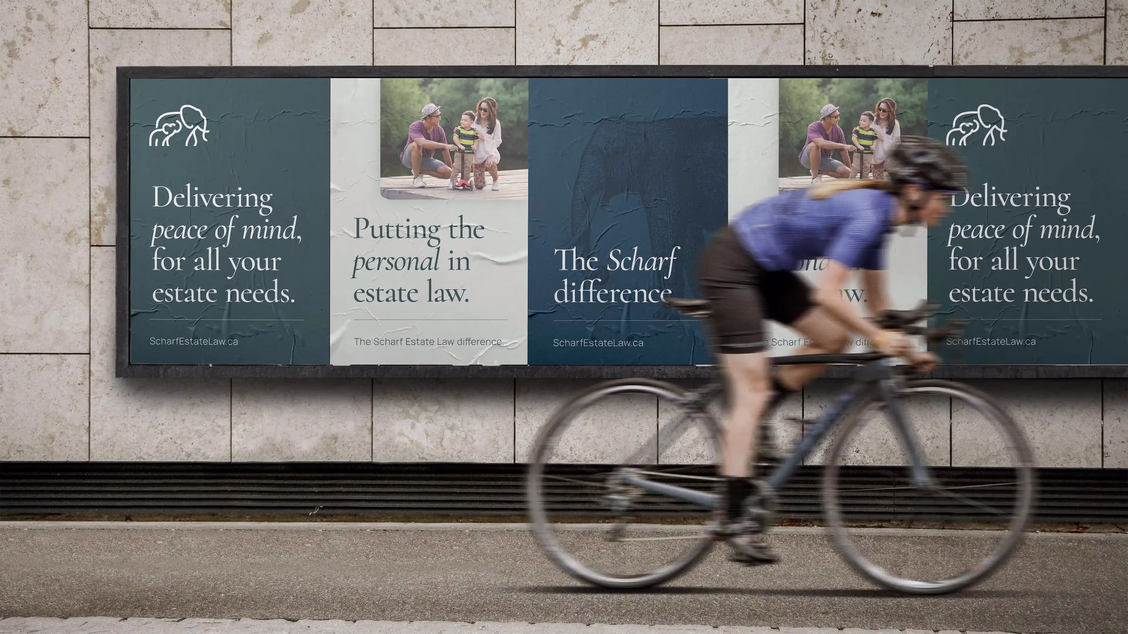 A street scene with a bicyclist riding in front of a set of posters for Scharf Estate Law that note that the company delivers peace of mind and puts the personal in estate law services.